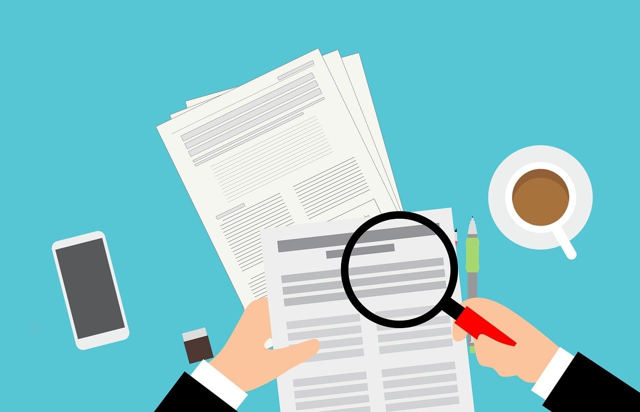 magnifying glass searching the newspaper